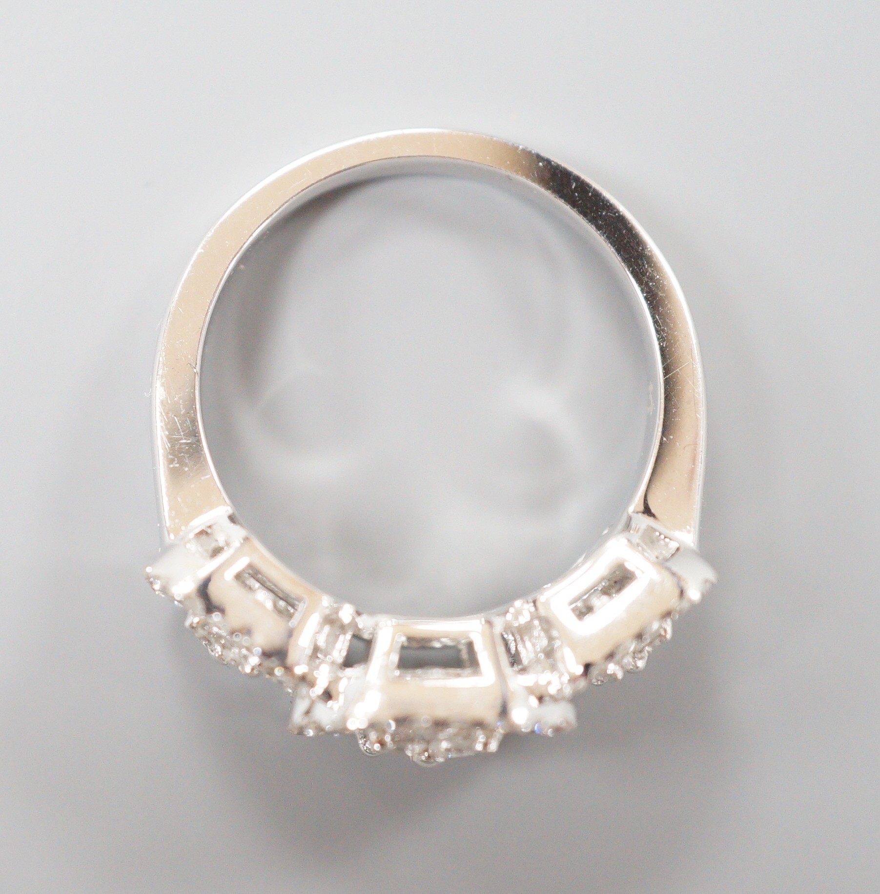 A modern 750 white metal, trapeze and round cut diamond set triple cluster dress ring, size M, gross weight 7 grams